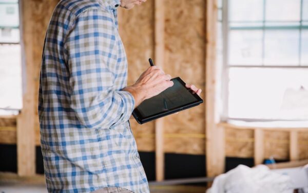 Roofer at job site home interior using roofing software on a tablet