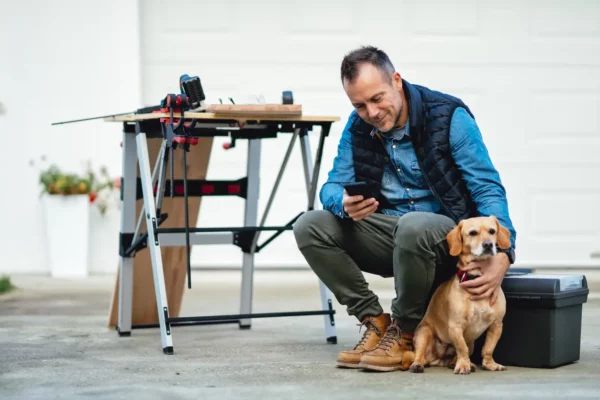 Man texting on his phone next to wood working tools