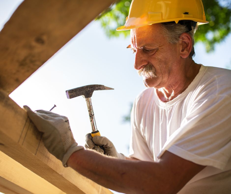 elderly roofer hammering a nail